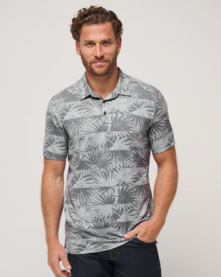 A man wearing a gray floral print polo shirt with short sleeves, paired with blue jeans.
