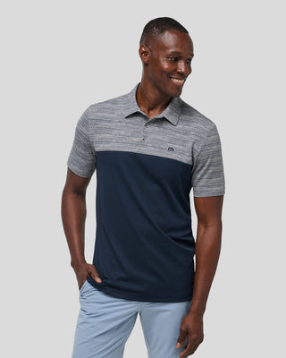 A man wearing a color-blocked Rocky Beach polo shirt with a subtle pattern, consisting of gray and navy blue colors.